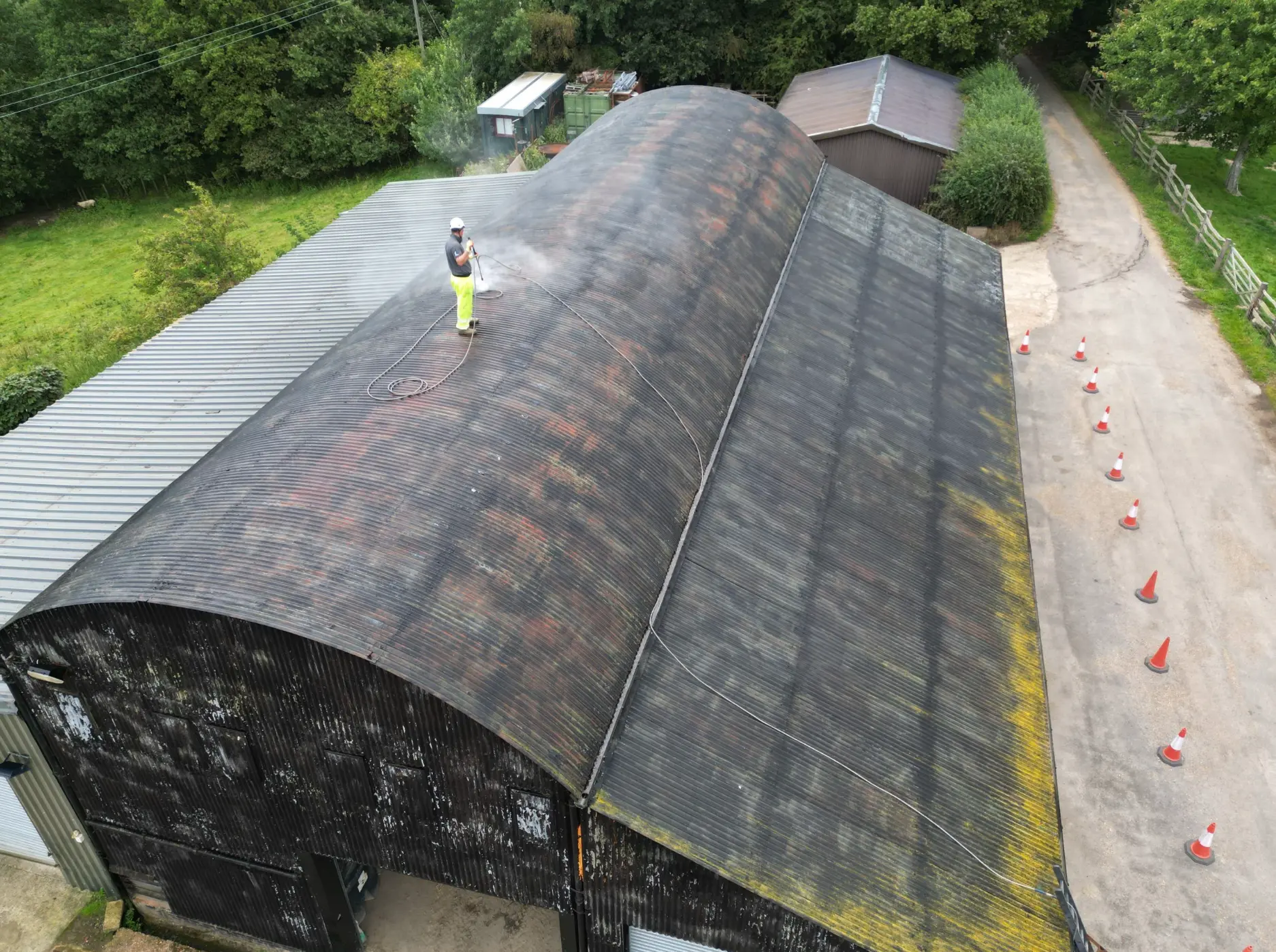 Operative cleaning a curved corrugated farm shed roof